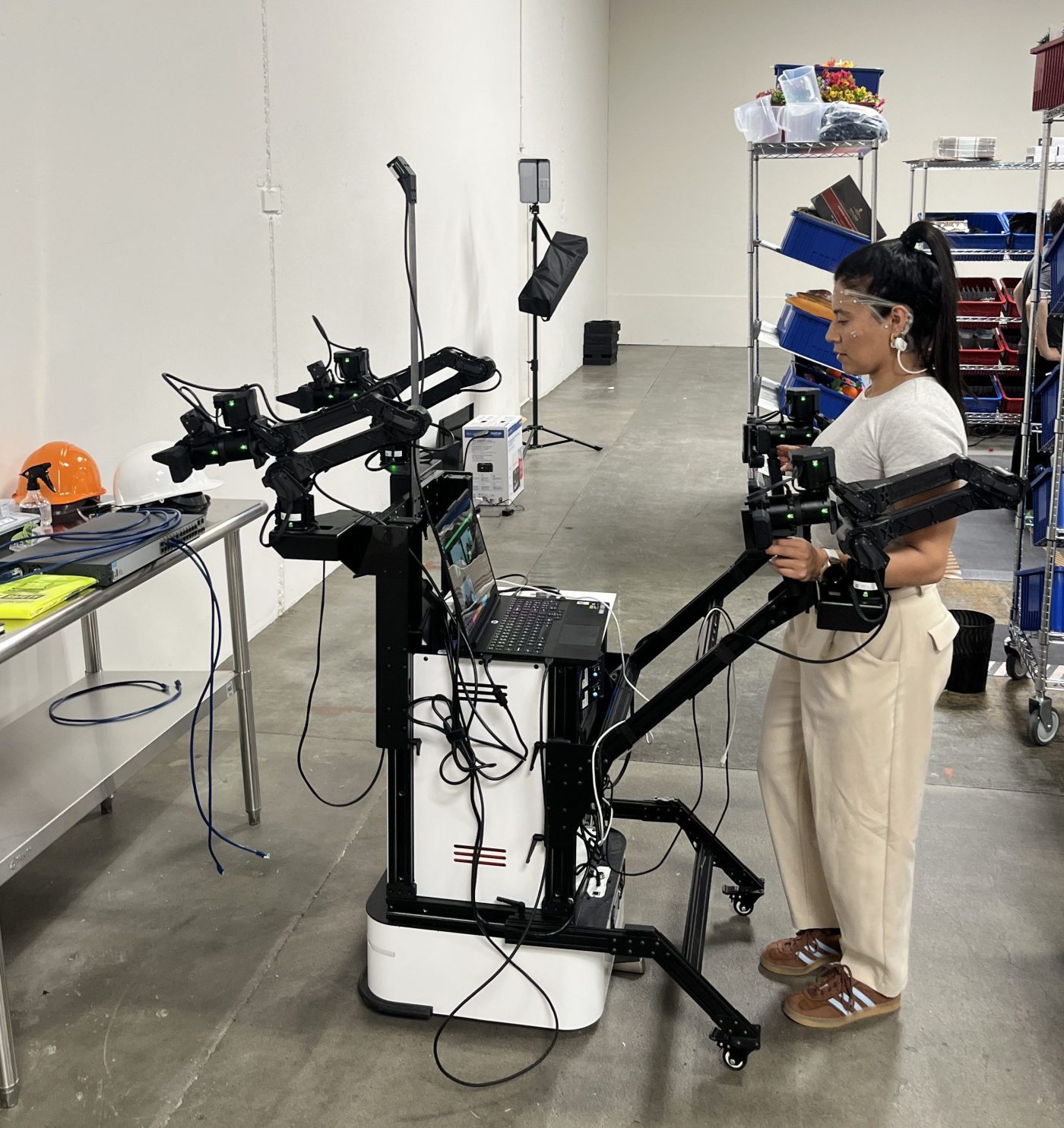 Une opératrice manipule un bras robotisé relié à des capteurs dans un entrepôt