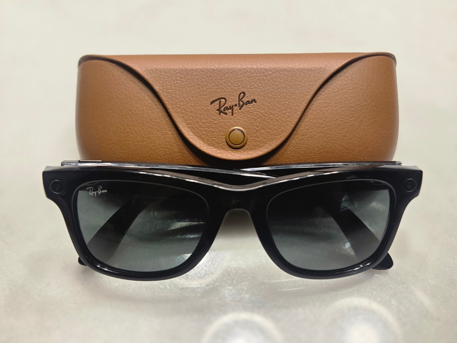 Une paire de lunettes connectées Ray-Ban Meta posée devant son étui.