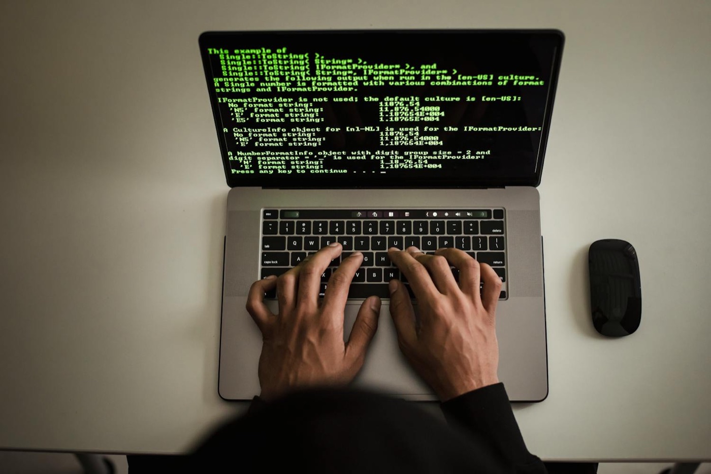 Un ordinateur portable faisant tourner un programme dans un terminal, texte en vert sur fond sombre